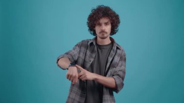 Öfkeli hippi, saatine kızgın bir şekilde bakıyor iş arkadaşlarının gecikmesine. Kıvırcık saçlı genç