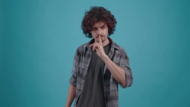 Genç hippi, parmağı dudaklarında, sessiz görünüyor, çok fazla tartışmaktan rahatsız..