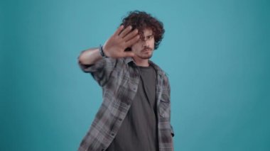 Rahatsız adam dur işaretini iki kez göstermek için elini kaldırır..