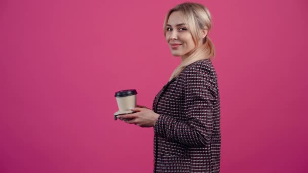 Хорошо расположенная молодая женщина, в профиль, улыбается, держа стойку с двумя чашками кофе — стоковое видео