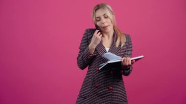 İş kadını, genç bir kadın telefonda konuşur ve bilgilerini not defterine kaydeder. Ve sonunda geniş bir şekilde gülümser..