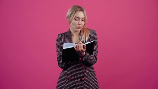 Słodka uczennica, notatki w pamiętniku, ciekawa. piękne młody Dojrzałe blondynka w różowy kurtka. — Wideo stockowe
