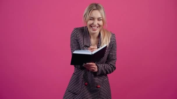 Als sehr fröhliche Studentin hält sie ein Notizbuch in der Hand und notiert mit einem Lächeln und genießt den Erfolg. — Stockvideo