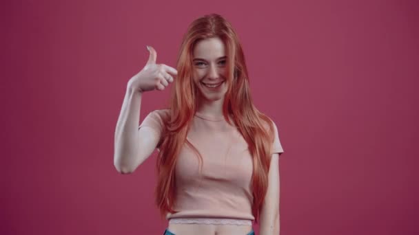 Large sourire d'une rousse, dans un T-shirt décontracté rose, isolé sur un fond rose. Le concept de style de vie des peuples. — Video