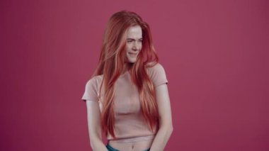 20 yıl boyunca pembe bir tişörtle, pembe arka planda izole edilmiş, tatminsiz kızıl saçlı..