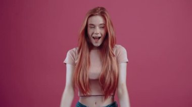 Şok olmuş, 20 yaşında, pembe tişörtlü, pembe arka planda izole edilmiş bir kızıl. İnsanların yaşam tarzı kavramı.