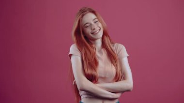 Genç, güler yüzlü, gösterişsiz, 20 yıl boyunca pembe tişörtlü, pembe arka planda izole bir şekilde neşeli. İnsanların yaşam tarzı kavramı.