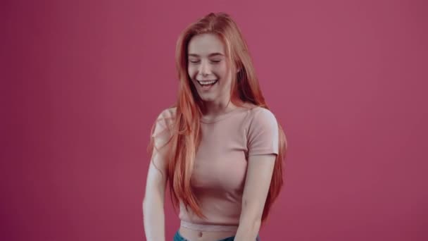 Das junge rothaarige Mädchen, im Profil, seit 20 Jahren fröhlich, in einem pinkfarbenen lässigen T-Shirt, isoliert auf rosa Hintergrund. Das Konzept des Lebensstils der Menschen. — Stockvideo