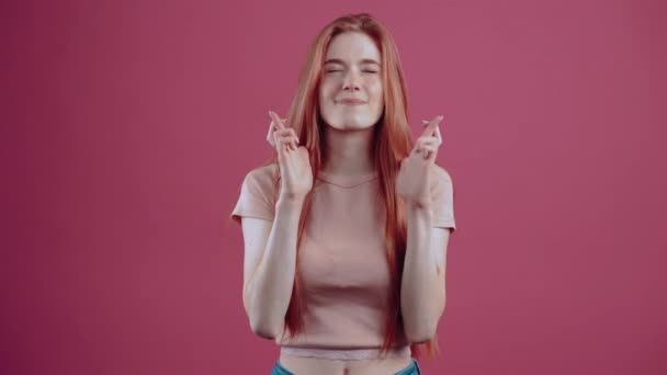 Mujer joven pelirroja suspendida, de perfil, 20 años, en una camiseta casual rosa, aislada sobre un fondo rosa. — Vídeos de Stock
