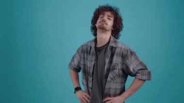 Elleri ortada olan genç adam odaya kibirle bakıyor ve gülümsüyor..
