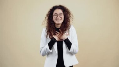 Kıvırcık saçlı neşeli genç bir kadın, yüksek sesle gülüyor, öne eğiliyor ve odayı işaret ediyor..