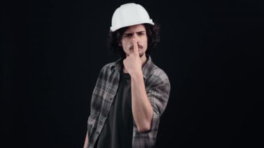 Kıvırcık saçlı, daracık kasklı, burnunda parmağı olan sinirli hippi işçi intikam gösteriyor. İnsanların yaşam tarzı kavramı. Sanayi.