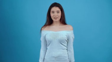 Şok olmuş, mutlu Asyalı gülüşü. Koyu renk saçlı, mavi bluz giymiş, stüdyoda koyu mavi bir arka planda izole edilmiş.