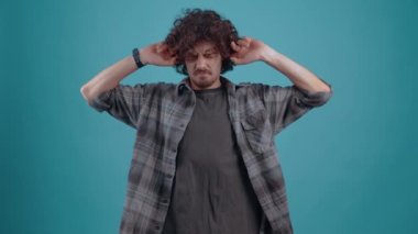 Genç hippi gürültüden çok rahatsız olmuştu, parmakları kulaklarında bağırıyor ve bağırıyordu, gürültüyü durdurmak için, stüdyoda turkuaz bir arka planda..