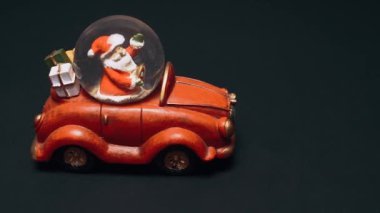 Araba şeklindeki oyuncak, kırmızı, bagajında hediyeler olan, direksiyonda Noel Baba olan. Çocuk oyuncakları, kış konsepti. Noel ve Yeni Yıl