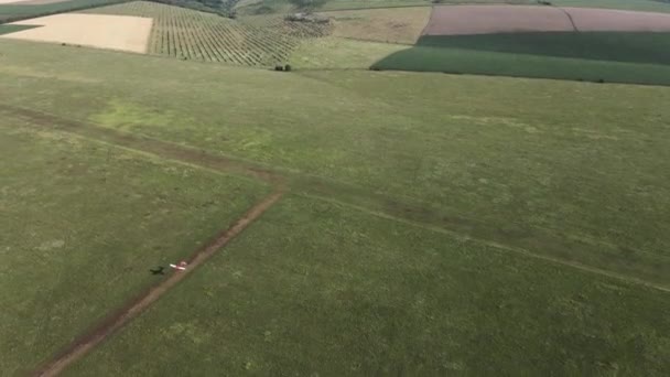 Flygvideo som visar ett litet rött plan som landar på ett fält. Ögonblicket då ett flygplan tvingades landa. Drönaren fångar ett plan som landar. Flygplansbanor. Vadul lui Voda flygplats i Chisinau. — Stockvideo