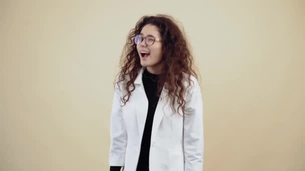 Linda joven con el pelo rizado, con la boca aguada, mira a la habitación, sonriendo lentamente. Joven hipster en chaqueta gris y camisa blanca, — Vídeo de stock