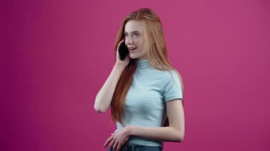 Huysuz genç bir kadının resmi bir telefon alıyor ve öfkeyle pembe arka planda izole edilmiş mavi bir tişörtle kapanıyor. İnsanların yaşam tarzı kavramı