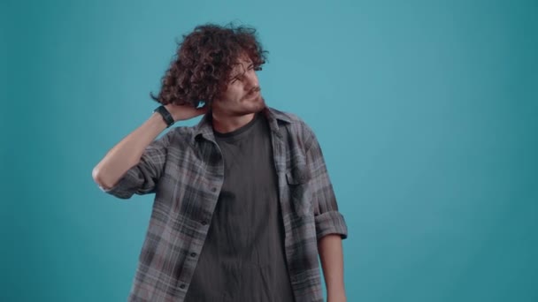 Ung irriterad hipster, pekar fingret i ansiktet och visar dåliga tecken, i studion på en turkos bakgrund. Begreppet livsstil — Stockvideo