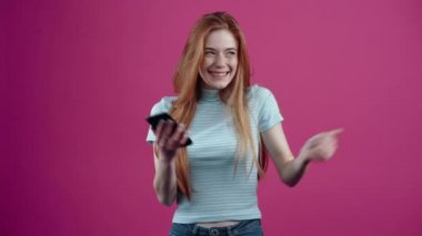 Elinde telefon olan genç kazananımız vay canına diyor ve pembe arka planda izole edilmiş mavi bir tişörtle mutlu bir şekilde gülümsüyor. İnsanların yaşam tarzı kavramı