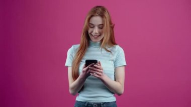 Güzel ve kızıl saçlı genç, mesaja geniş bir gülümsemeyle tepki verir ve sohbetin konusu olana, pembe bir tişörte izole edilmiş sıradan bir mavi tişörte, eğlenceli bir şekilde işaret eder.