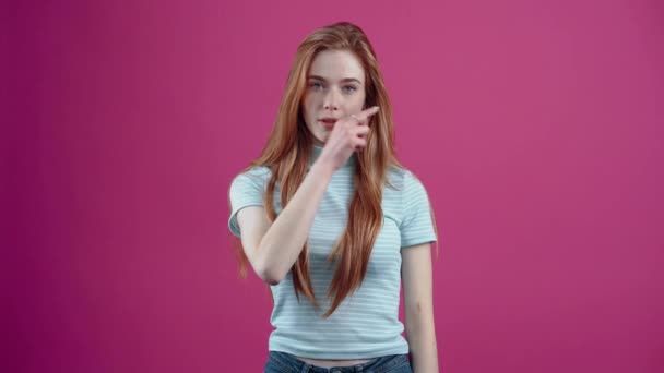 La joven pelirroja comprensiva jura guardar un secreto cerrando la boca y lanzando la llave, en una camiseta azul casual, aislada sobre un fondo rosa. El concepto de estilo de vida de las personas — Vídeos de Stock