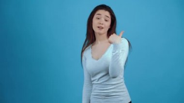 Genç, küstah esmer hareketler dikkatleri üzerine çekmek için, onu işaret ediyor. Koyu saçlı, mavi bluz giymiş, stüdyoda koyu mavi bir arka planda izole edilmiş bir Asyalı. Şey...