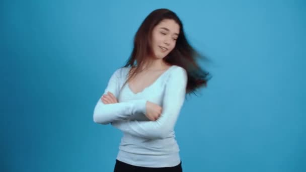 La jeune brune, confiante, posa fièrement ses mains sur sa poitrine et secoua les cheveux avec confiance. Asiatique aux cheveux foncés, vêtu d'un chemisier bleu, isolé sur un fond bleu foncé en studio. L ' — Video