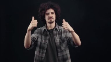Charismatic young man, relaxed, moving to the rhythm of music, improvising simple dance movements, closing his eyes, enjoying the moment. Isolated on black background, Concept of life. Peoples