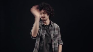 The optimistic young man laughs out loud with his hand on his stomach, pointing with his finger in front,