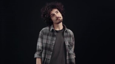 The charismatic young man, thoughtful, walks around looking for a solution, then shows a small smile as a sign that he has found the answer. Isolated on black background, Concept of life. Peoples