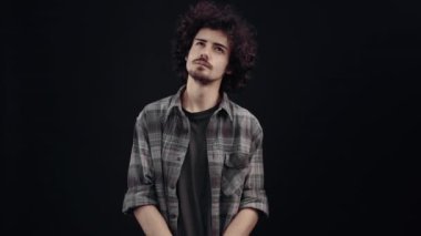 The young strategist, thoughtful, looks in parts, puts his hand on his chin, after which he happily displays the like sign because he has found a brilliant solution. Isolated on black background