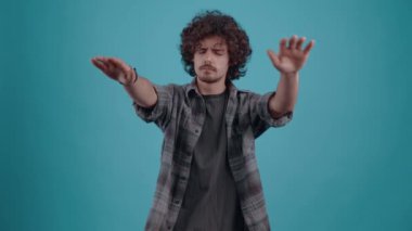 The focused young man closes his eyes and stretches out his hands to find what he is looking for. They play hide and seek. Isolated on black background, Concept of life. Peoples emotions. 4k portrait