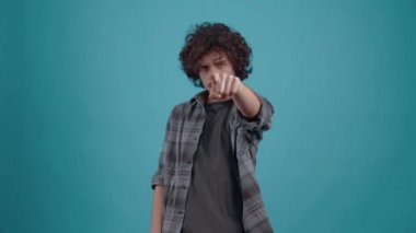 The sarcastic young man puts a hand to his forehead and shows the sign of loser, and with the other he points with his index finger in front. Isolated on black background, Concept of life. Peoples