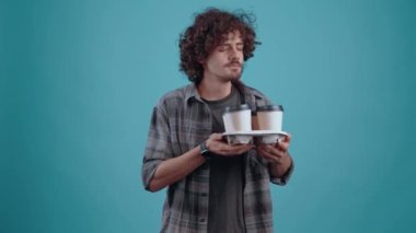 The charismatic brunette smells the inviting aroma of coffee and blinks often, nodding. Isolated on black background, Concept of life. Peoples emotions. 4k portrait