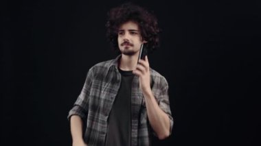 The chalky young man receives a call that confuses him, he says what and then closes the irritated call. Isolated on black background, Concept of life. Peoples emotions. 4k portrait