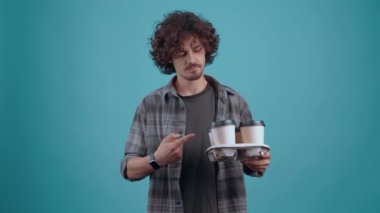 The charismatic brunette sits with four glasses of coffee in her hand, looks like and with her hand on her stomach shows that she is tasty. isolated over turquoise background. Concept of life. People