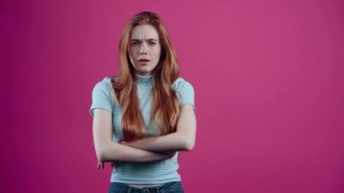 Genç kızıl saçlı öfkeyle ellerini göğsünün üzerinde çapraz yapar, gürültüden rahatsız olan kulaklarını öfkeyle kapatır. Pembe arka planda mavi tişörtlü çilli genç. Şey...