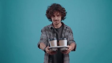 Neşeli öğrenci, arkadaşına içtenlikle içmesini teklif ettiği 4 bardak kahveyi dağıtır. Turkuaz bir arka planda izole edilmiş. Hayat kavramı. İnsanların duyguları işte. 4k