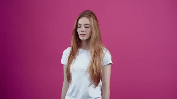 You are guilty. The angry young woman points with her index finger in front and puts her hand firmly on her hip. Freckled teenage girl in a white T-shirt, isolated on a pink background. The concept of — Stock Video