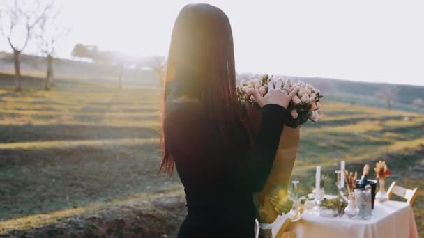 Wanita muda yang bahagia, terisolasi di dada alam, memegang dalam pelukannya karangan bunga besar, dan dengan satu tangan dia menunjukkan cincin pertunangan yang dia terima dari pacarnya, di romantis — Stok Video