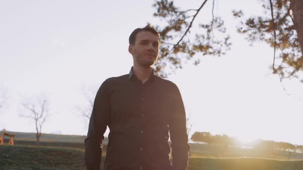 El hombre seriamente aislado en la naturaleza mira pensativamente en partes y admira la belleza de la naturaleza al atardecer — Vídeos de Stock