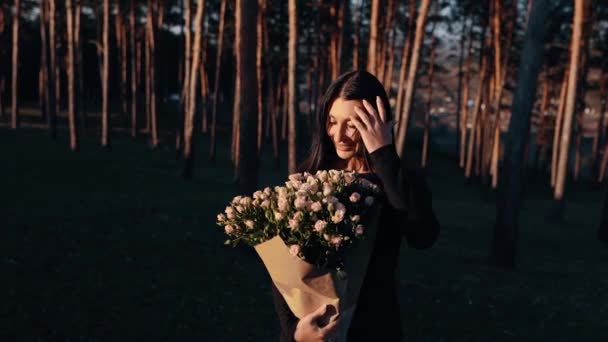 Молодая женщина, изолированная в лоне чрезвычайно счастливой природы, нюхает букет цветов, играет с волосами, с гордостью поднимает букет — стоковое видео