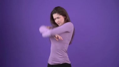 Kızgın genç kadın ellerini göğsünün üstüne koyuyor ve üzgün görünüyor. Mor bir arka planda, mor bir kazak giymiş esmer kadın. Yaşam tarzı kavramı