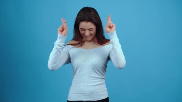 La hermosa y carismática chica sostiene sus dedos cruzados en ambas manos, espera que el deseo se haga realidad. Asiático con el pelo oscuro, vestido con una blusa azul, aislado sobre un fondo azul oscuro en — Vídeos de Stock