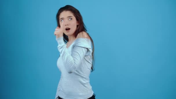 O retrato de uma jovem segurando o dedo indicador na frente e abrindo a boca na forma de, então ela entendeu. Asiático com cabelo escuro, vestido com uma blusa azul, isolado em um azul escuro — Vídeo de Stock