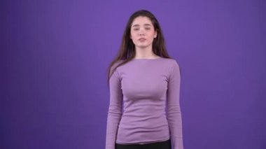 Konsantre olan dengeli genç bir kadının portresi mütevazı bir gülümseme sergiliyor. Mor bir arka planda, mor bir kazak giymiş esmer kadın. Yaşam tarzı kavramı