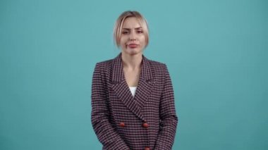 Hoş olmayan bir şey dinleyen, kaşlarını çatan ve başını sallayan genç bir kadının portresi. Turkuaz bir arka planda izole edilmiş. Hayat kavramı. İnsanların duyguları işte. Dikey 4k