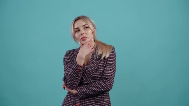 The thoughtful young entrepreneur puts her hand to her chin to think of a solution, raises her finger and displays a smile when an idea comes to her. Isolated on a turquoise background. The concept of — Stock Video