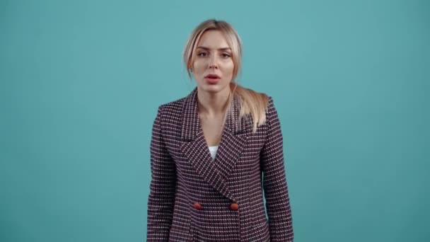 The portrait of a girl frightened by what she sees in front of her, she terrifiedly puts her hands to her cheeks and opens her mouth in shock. Isolated on a turquoise background. The concept of life — Stock Video